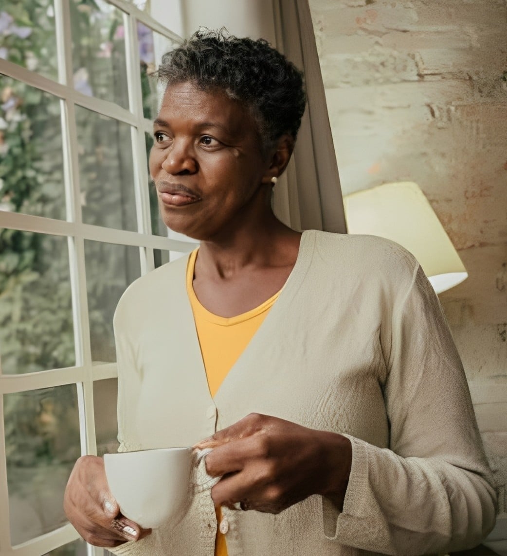 Woman with a cup of tea looking out the window, at peace knowing her final arrangements are in place